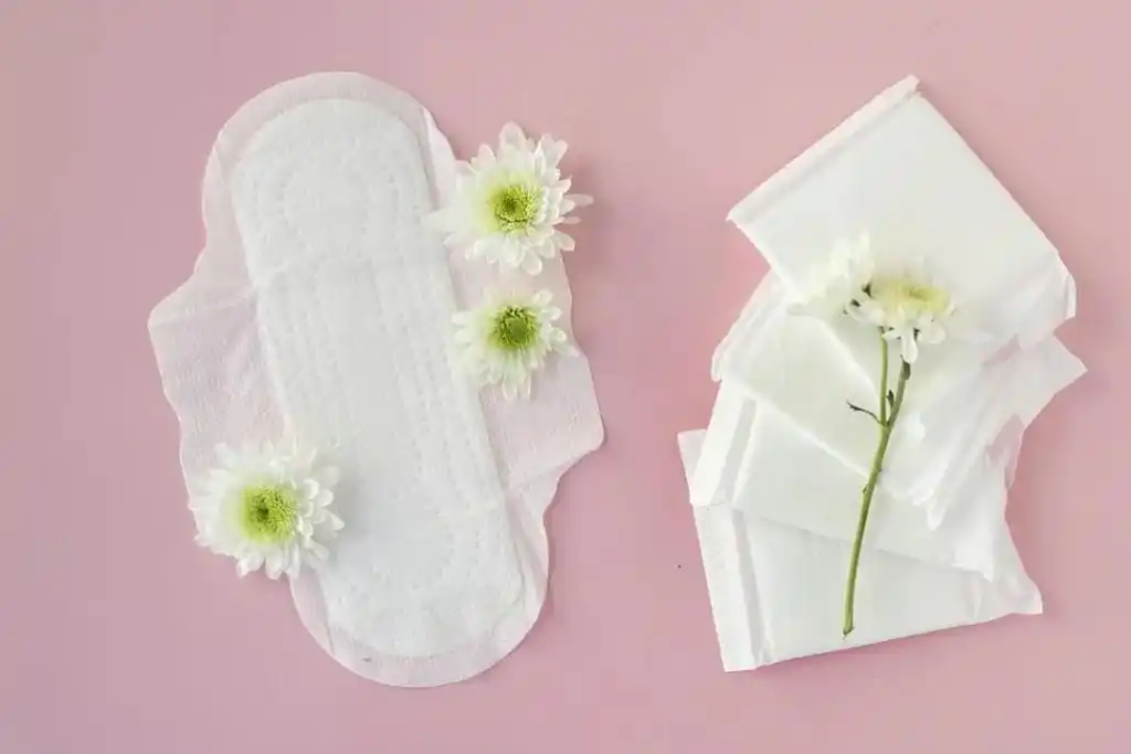 A woman looking at an old box of sanitary pads in her bathroom drawer, appearing thoughtful or unsure.