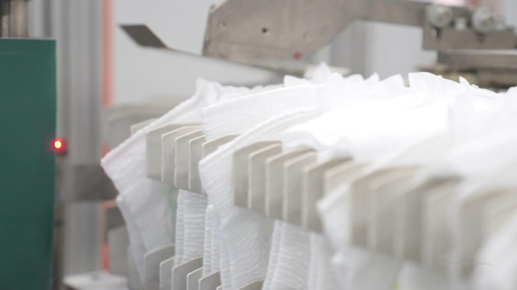 A brand representative reviewing baby diaper samples and packaging received from an OEM factory.